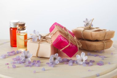 El yapımı Sabunlar, çiçek, uçucu yağlar ve ahşap masa üzerinde deniz tuzu