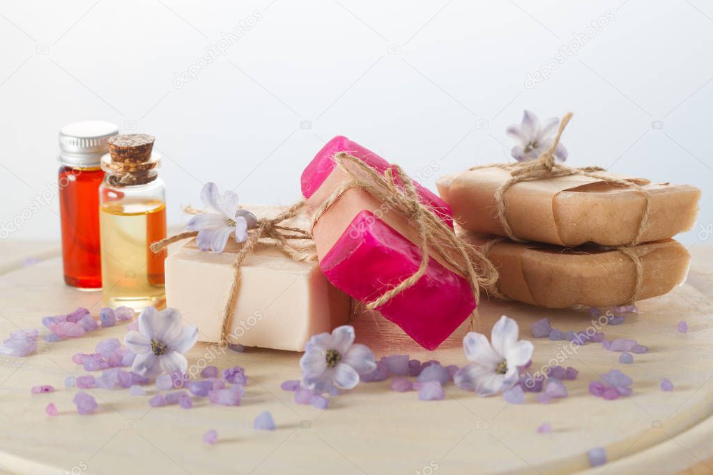 Handmade soaps, flowers, essential oils and sea salt on wooden table