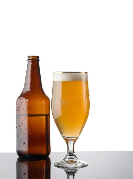 Craft beer bottle and beer in glass on glass table isolated on white