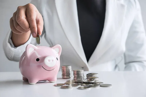 Business woman putting coin into pink piggy bank for planning st — Stock Photo, Image