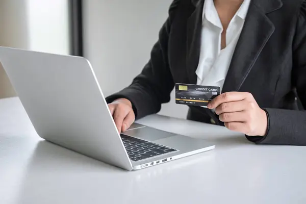 Ділова жінка споживач тримає кредитну картку і друкує на ноутбуці — стокове фото