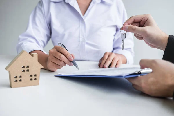 Estate agent giving house keys to client after signing agreement