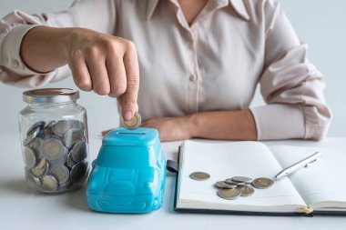 Yükselen iş için mavi domuz kumbarasına para koyan kadın.