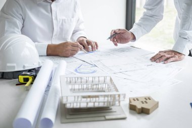 İnşaat mühendisliği ya da mimar bir proje planı ve inşa modelini tartışırken, aynı zamanda şantiyedeki mimari proje için yapılan çizim toplantısının bilgilerini kontrol ediyor..