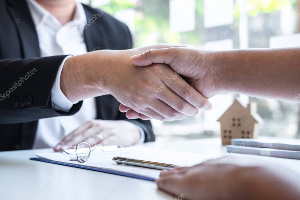Finishing to successful deal of real estate, Broker and client shaking hands after signing contract approved application form, concerning mortgage loan offer for and house insurance.
