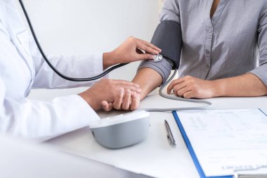 Doktor kan basıncını ölçerek hastayı muayene ederek, sonuçları sunarak ve tedavi yöntemi, sağlık ve tıbbi konsept önererek ölçüyor..