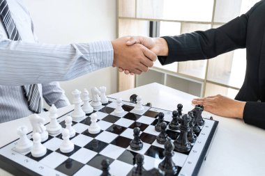 İş adamı ve iş kadını satranç oynadıktan sonra el sıkışıyor ve strateji çöküşünü düşünüyor karşı takımı deviriyor ve galibiyet ve başarı için geliştirme analizi yapıyor..