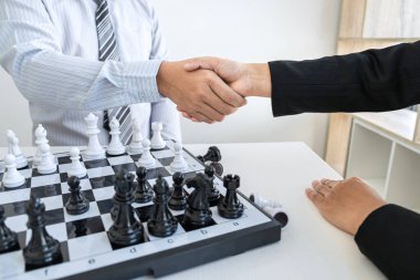 İş adamı ve iş kadını satranç oynadıktan sonra el sıkışıyor ve strateji çöküşünü düşünüyor karşı takımı deviriyor ve galibiyet ve başarı için geliştirme analizi yapıyor..