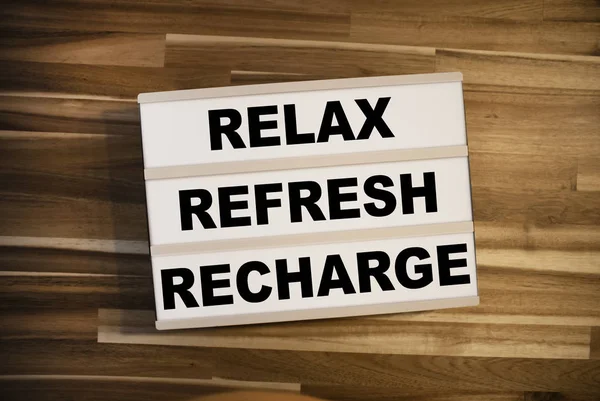 Lightbox or light box with message Reflex Refresh Recharge on a wooden table