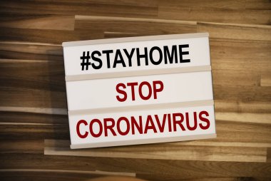 Işık kutusu ya da ışık kutusu covid 19 evde kal ve tahta masa arkasındaki Corona virüsünü durdur.