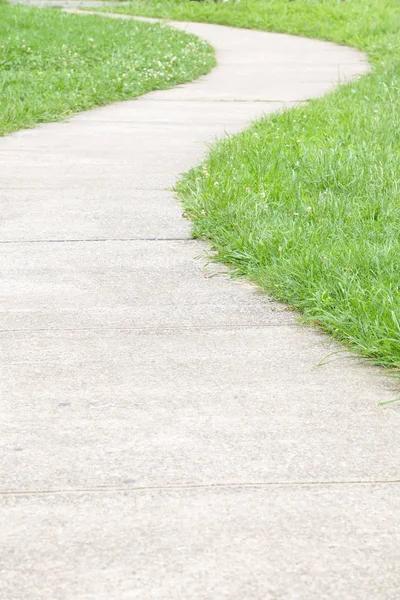 Zöld fű között betonon gyalogjárda — Stock Fotó