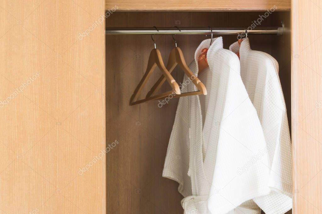  White bathrobe with hanger in wardrobe at hotel room