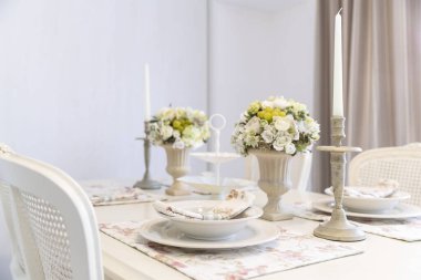 Çiçekler ve mumlarla süslenmiş yemek masası. 