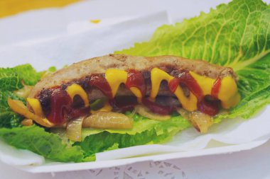 Sarı hardallı sosisli sandviç. Arka plan, Tayland sokak yiyecek pazarı.