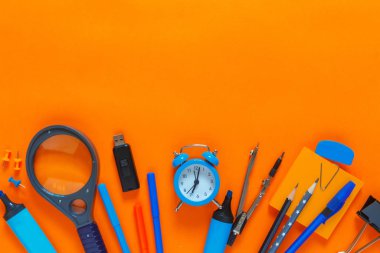 Back to school. Flat lay creative set of school supplies, notebook, pens, markers, alarm clock, compass. School background orange color