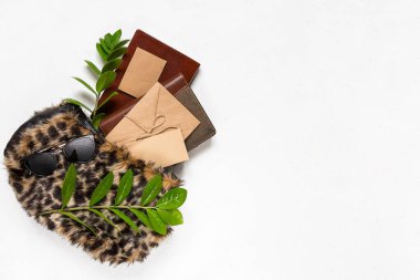 Yeşil dallı leopar desenli kürk, yeşil yapraklar, fırçalar, kozmetik ürünler, planör, güneş gözlüğü arkaplan. Üst Manzara. Moda çantalı kadın aksesuarları. Yaz moda yatağı.