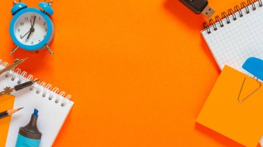 Back to school. Flat lay creative set of school supplies, notebook, pens, markers, alarm clock, compass. School background orange color
