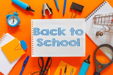 Creative flat top view of the position of school supplies stationery, education elements on an orange background. Concept back to school template for your text or design.