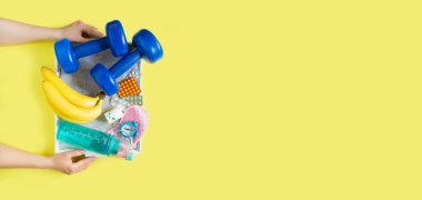 Biohacking health treatment with the help of sports, healthy nutrition, sleep and vitamins. Woman's hands hold a tray with a set for biohacking on a yellow background flat view