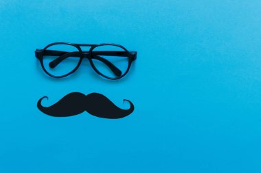 Father's Day. Bright holiday greeting card with the attributes of men mustache glasses on a bright blue-pink background. Flat top view