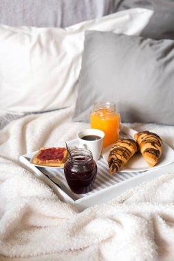 Yatakta kahvaltı, bir tepsi kahve, kruvasan, reçel, çiçekler. Balayı. Sabahın erken saatlerinde otelde. Yukarıdan görüntüle. 