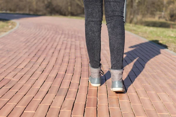 Gri Spor Ayakkabılı Siyah Kotlu Bir Kızın Bacakları Yolda Yürüyor — Stok fotoğraf