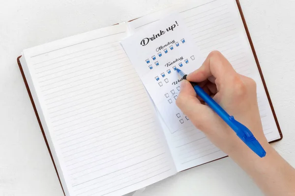 Water tracker, female hand notes the number of drinking glasses of water in the habits tracker, the idea of a healthy lifestyle and metabolism — Stock Image Water Tracker Female Hand Notes Number Drinking Glasses Water Habits Royalty Free Stock Images