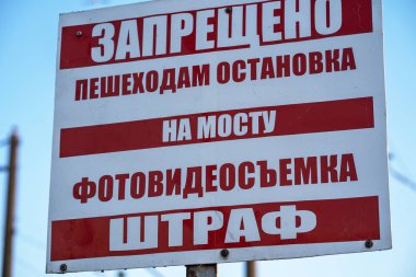 İlan panosunda yürümeyi, fotoğraf çekmeyi ve video çekmeyi yasaklayan ilan panosu kırmızı harflerle yazılmıştır: Yayaların köprüde durması yasaktır, fotoğraf ve video çekimi yasaktır, tamam