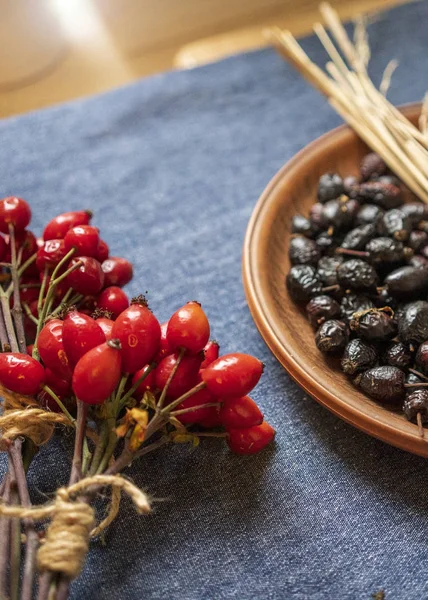 Rosehip berries, buckwheat honey in jars, cinnamon, dried pineapples, star anise on a blue background. Vertical frame, top view, space for copy space.