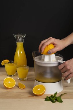 Sadece bir kadın meyve sıkacağı ile meyve suyu sıkar tahta arka planda bir kaç dilim portakal dilimi