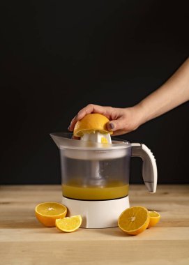 Sadece bir kadın meyve sıkacağı ile meyve suyu sıkar tahta arka planda bir kaç dilim portakal dilimi