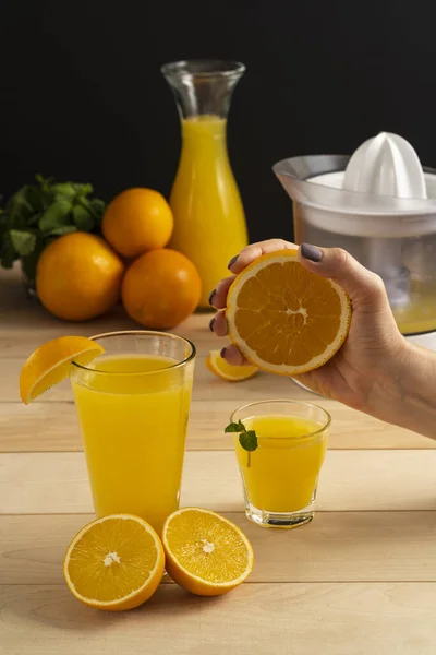 only female hand squeezes juice with a juicer on a wooden background a few cut orange slices