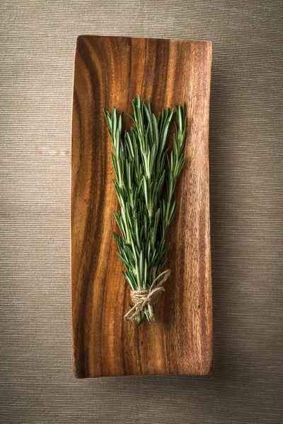 Ramitas de romero sobre un plato de madera — Foto de Stock