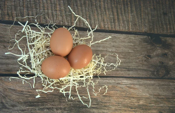 Τρία Αυγά Κότας Μια Φωλιά Άχυρου Ένα Ξύλινο Τραπέζι Κοντινό — Φωτογραφία Αρχείου
