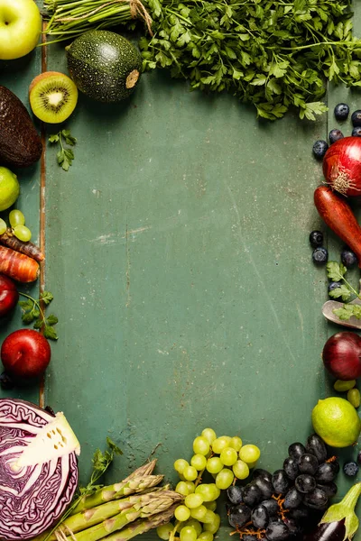 Assortment of raw organic fruits and vegetables: eggplants, onions, berries, carrots, grapes, cabbage, avocado, plums over rustic background, gluten free, allergy-friendly, clean eating or raw diet. Top view with space. Food frame — Stock Image Assortment Raw Organic Fruits Vegetables Eggplants Onions Berries Carrots Grapes Royalty Free Stock Images