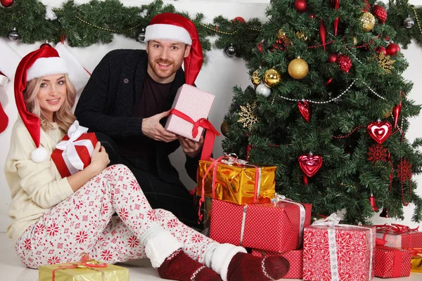 Pareja Enamorada Sentada Junto Árbol Navidad Bien Decorado Sosteniendo Regalos — Foto de Stock
