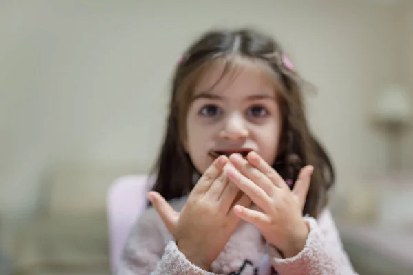 可愛いです女の子食べる驚きチョコレートとともに面白いです顔見ながらカメラ — ストック写真