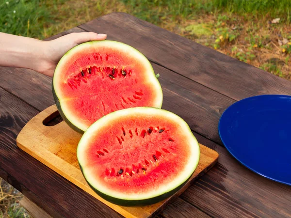 Kvinnliga Händer Skär Mogen Vattenmelon Ett Träbord Med Kniv — Stockfoto