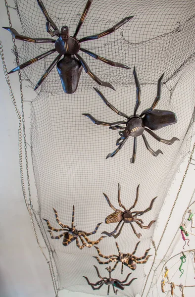 Steel spider figures on a black net on display