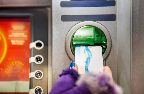 Hands of woman with gloves pulls in debit card at an ATM.ATM cash terminal with display