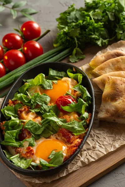 Jajka smażone z pomidorami i ziołami w owalnym czarnym naczyniu — Zdjęcie stockowe