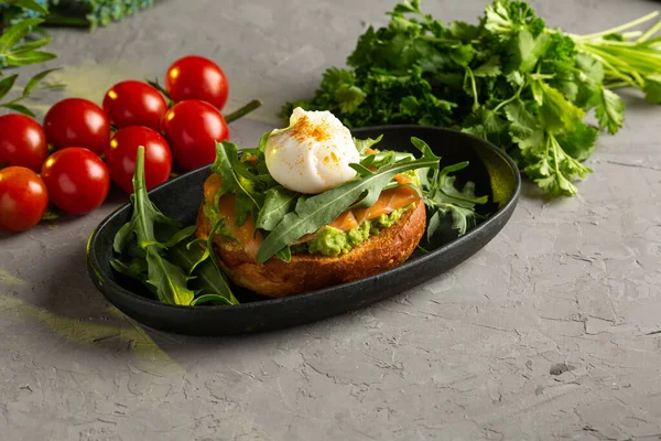 Avokado soslu bruschetta somonu. Guacamole, roka ve kızarmış ekmeğin üzerinde haşlanmış yumurta ile tuzlanmış somon.