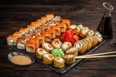 Suşi seti. Sos ve yemek çubuklarıyla siyah tahta bir zeminde.