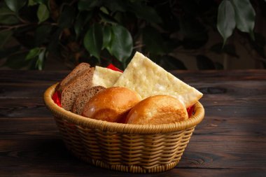 Koyu ahşap bir arka planda sepetteki çeşitli ekmekler.