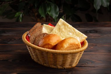 Koyu ahşap bir arka planda sepetteki çeşitli ekmekler.