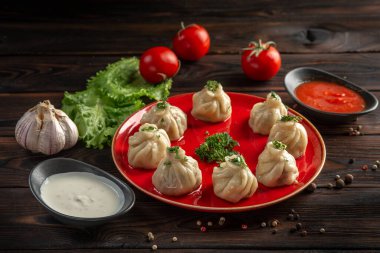 Kırmızı tabakta sığır eti ve koyu ahşap arka planda bir fincanda sos.