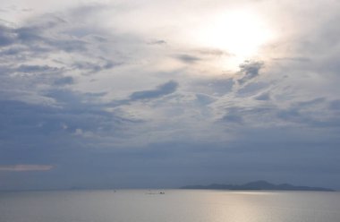 Sakin suyla manzaralı deniz manzarası, bulutlu gökyüzü ve ufuktaki dağların silueti fırtınadan önce