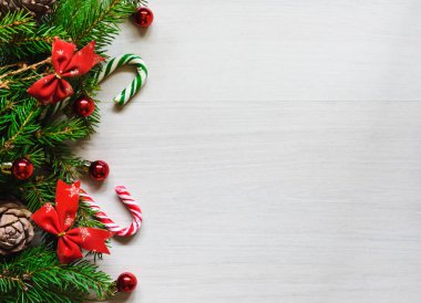 Noel kompozisyonu, kırmızı yaylı kozalaklı köknar dalları, hafif arka planda oyuncaklar ve tatlılar