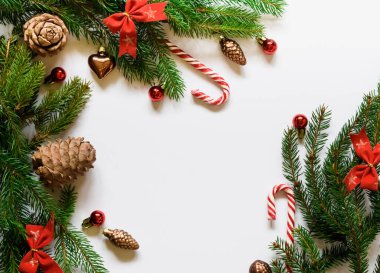 Üst manzara, ladin yeşil dalları yeni yıl oyuncakları ve beyaz arka planda fiyonklar.