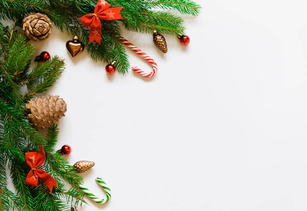 top view, green branches of spruce together with New Year's toys and bows on a white background